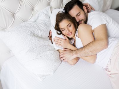 Pár v objatí spiaci na posteli.