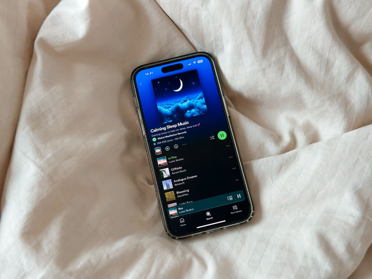 Playlist relaxačnej hudby na smartfóne položenom na posteli.